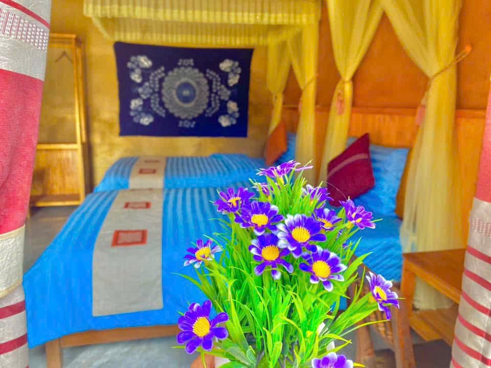 A homestay room with canopy beds and fresh flowers