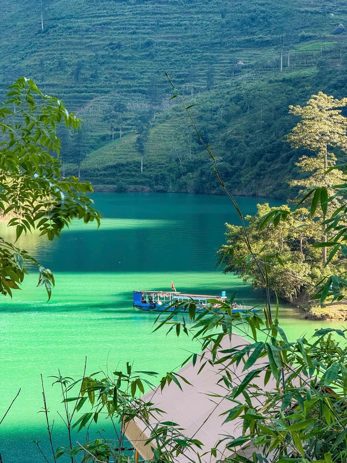 A boat on a turquoise river below terraced hills